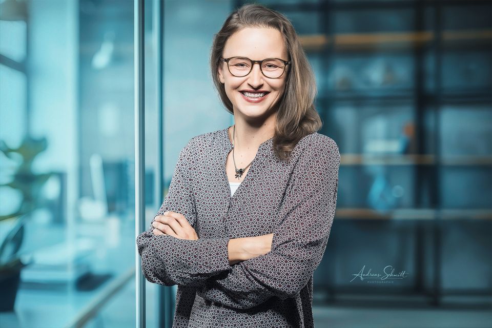 Businessportrait einer Frau mit verschränkten Armen vor Glaswand
