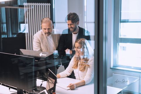 Drei Mitarbeitende arbeiten gemeinsam an einem Schreibtisch im Büro