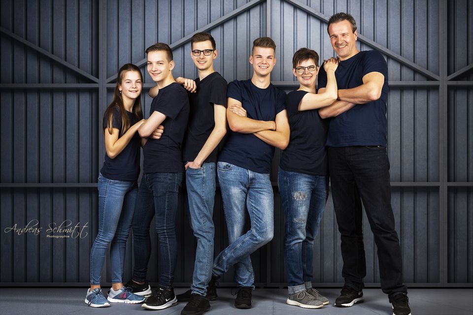 Familie mit Söhnen vor Holztor