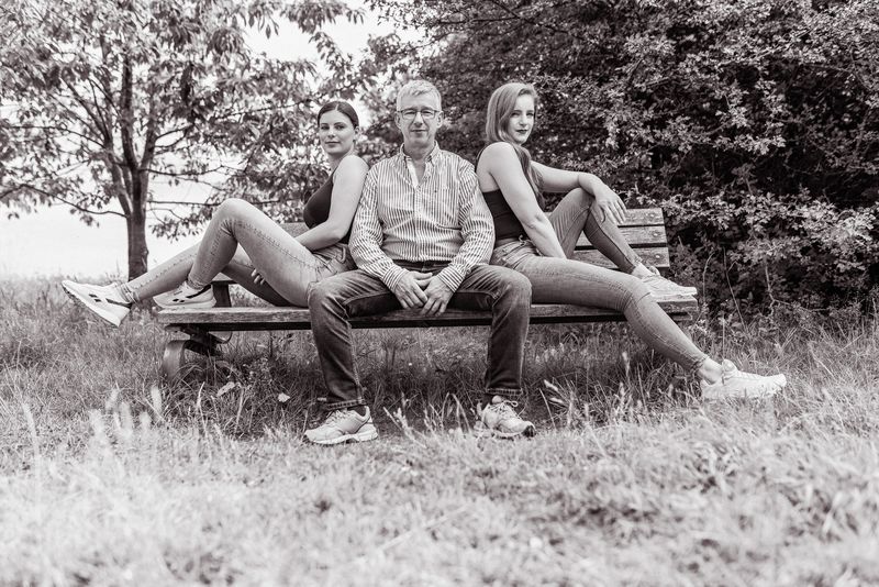 Familie sitzt auf einer Bank im Park, Schwarzweiß