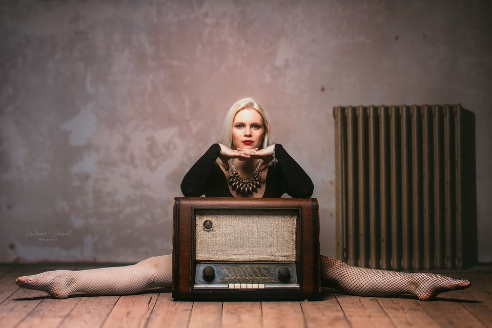 Frau im Spagat hinter einem alten Radio