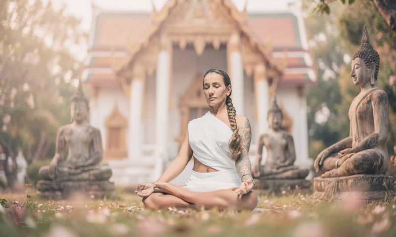 Frau meditiert zwischen Buddha-Statuen