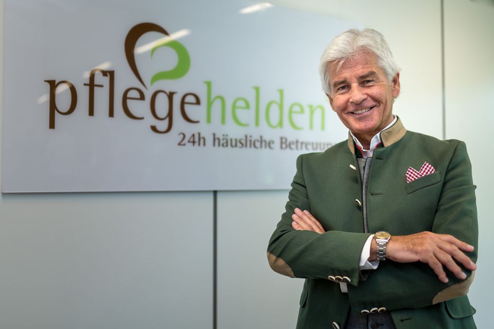 Geschäftsführer mit verschränkten Armen vor dem Firmenlogo am Empfang