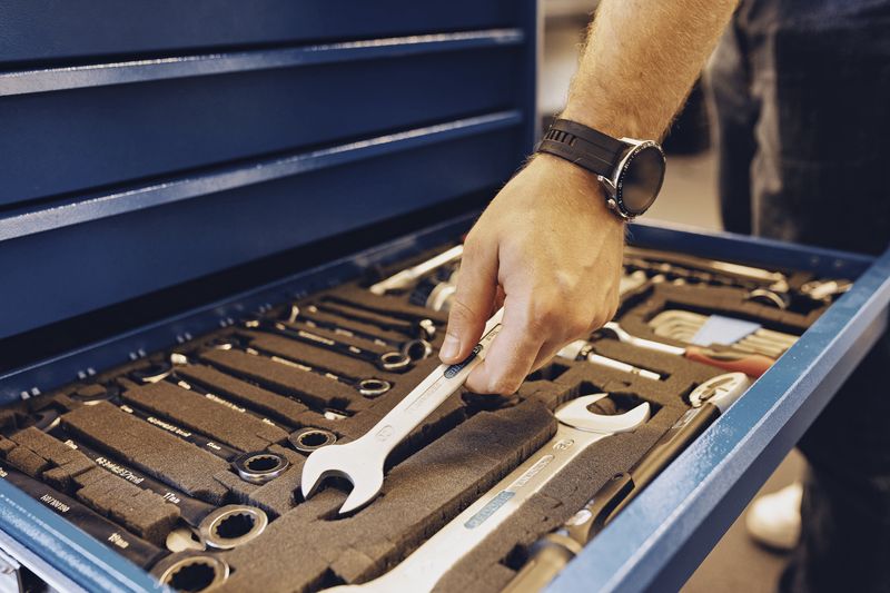 Hand nimmt einen Schraubenschlüssel aus einer Werkzeugschublade