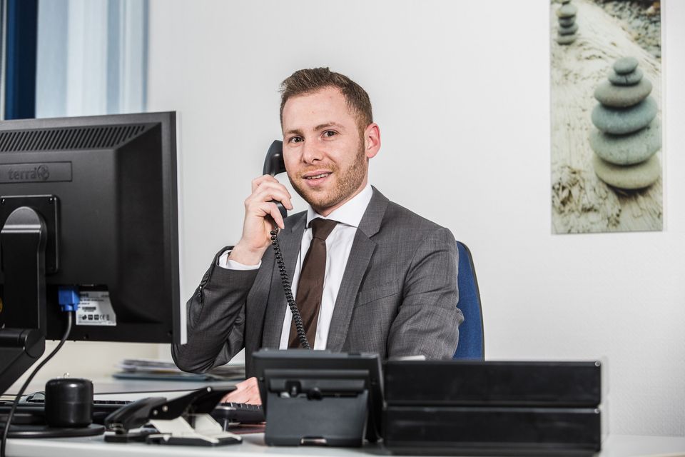 Mann im Anzug telefoniert am Schreibtisch