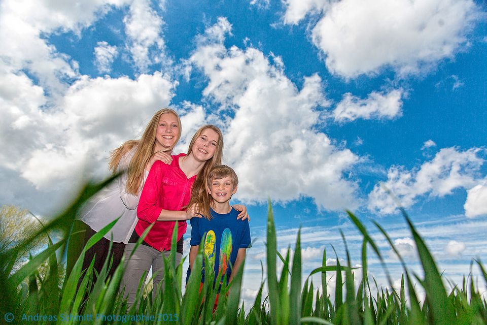 Mutter mit drei Kindern auf einer Wiese unter blauem Himmel