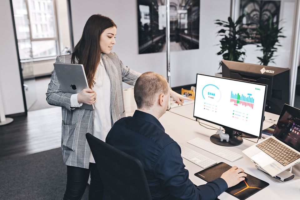 zwei Mitarbeiter schauen zusammen auf einen Monitor